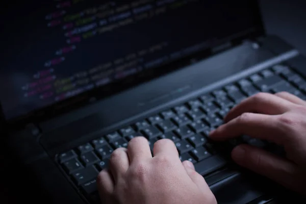 Internet hacker hırsız kavramı. Hacker dizüstü bilgisayar ekipmanı saldırmak için kullanma. Karanlık ve korkunç aydınlatma. Bir sürü bilgisayar ekranında sembolleri. Seçici odak.