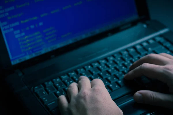 Internet hacker hırsız kavramı. Hacker dizüstü bilgisayar ekipmanı saldırmak için kullanma. Karanlık ve korkunç aydınlatma. Bir sürü bilgisayar ekranında sembolleri. Seçici odak.