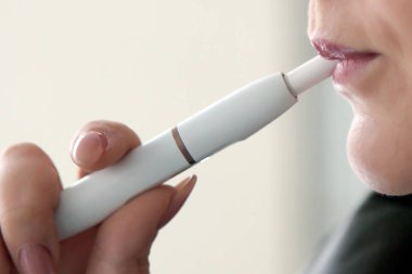Bir genç kadın sigara elektronik sigara. Elektronik Sigara bir kadınla Close-up. Yeni teknoloji elektronik sigara sistemi. Tütün sistem Iqos.