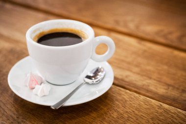 bir fincan kahve bize bir daire ve bir kaşık ahşap bir masa üzerinde duruyor. aromatik sıcak taze kahve. çapraz çizgiler ile ahşap antika masa arka plan. tasarımı ve dekorasyonu için. seçici odak