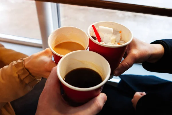 close up hands with coffee cups at cheers time. friends have fun and drink coffee in the cafeteria