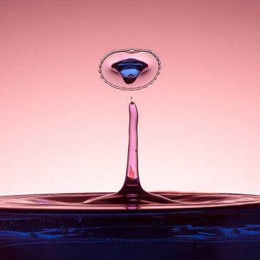 An iki su damlacıkları bir taç oluşturan çarpışır. Sıvı mavi renklidir ve arka pembedir. Su sıçrama kopya alanı ile