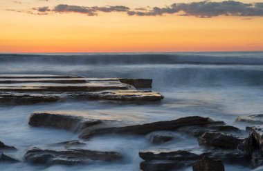 Limasol, Kıbrıs'taki Akrotiri bölgesinde kayalık bir kıyısında dramatik güzel gün batımı. Uzun pozlama fotoğraf
