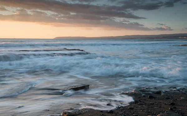 Bir kayalık sahil üzerinde dramatik güzel gün batımı. Uzun pozlama fotoğraf