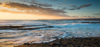 Limasol, Kıbrıs'taki Akrotiri bölgesinde kayalık bir kıyısında dramatik güzel gün batımı. Uzun pozlama fotoğraf