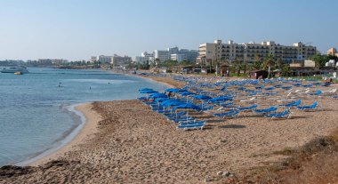 Protaras, Kıbrıs - 29 Temmuz 2009: Beach boş şemsiyeleri ve sandalyeler turist Protaras, Kıbrıs'ta tesisi alanı plaj bekliyor