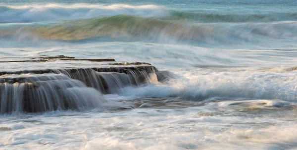 Rotsachtige kust met golvende oceaan en golven die neerstorten op de rotsen — Stockfoto