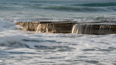 Dalgalı okyanusları ve kayalara çarpan dalgaları olan kayalık sahil kıyısı. 