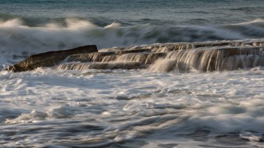 Dalgalı okyanusları ve kayalara çarpan dalgaları olan kayalık sahil kıyısı. 