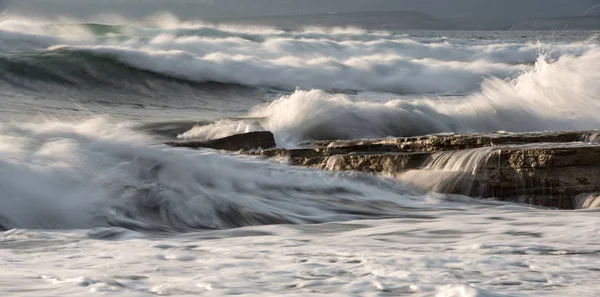 Sziklás tengerpart hullámos óceánnal és hullámokkal a sziklákon. — Stock Fotó