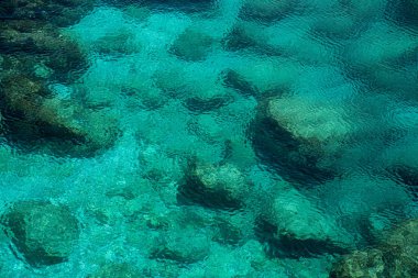 Kayalık bir sahil üzerinde açık mavi sakin deniz suyu arka plan