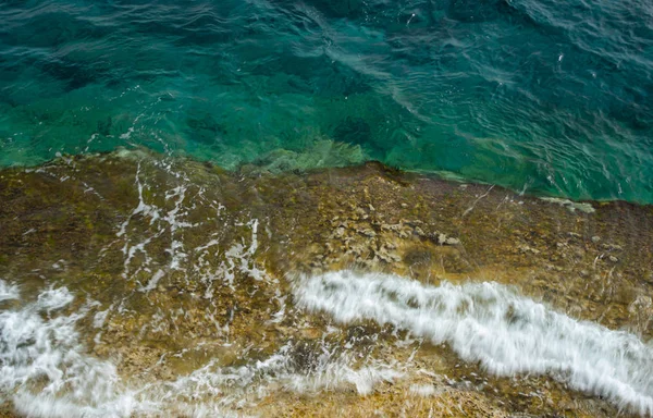 Helder blauw kalm zeewater achtergrond op een rotsachtige kust — Stockfoto