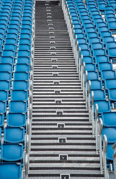 Cadeiras de estádio vazias de plástico azul em uma fileira — Fotografia de Stock