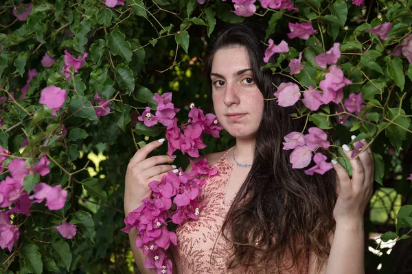Приваблива молода красива леді, насолоджуючись рожевими квітами — стокове фото