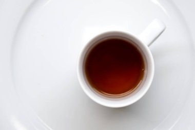 Siyah ferahlatıcı ve enerji verici çay beyaz bardakta masanın üstünde