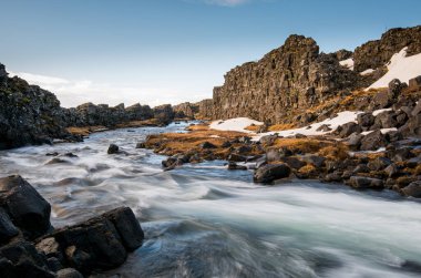 Şelaleden akan su İzlanda 'nın kayalık bir nehrine sıçrıyor.