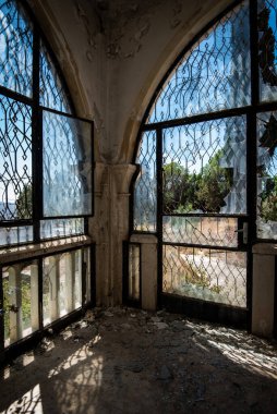 Kırık pencere ve kapılardan manzaralı terk edilmiş bir veranda odası.