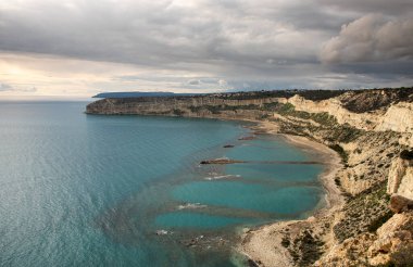 Kıyı kayalık deniz manzarası, uçurumlar ve gün batımında bulutlu ve fırtınalı bir gökyüzü. Zapalo Körfezi, Episkopi Limasol Kıbrıs