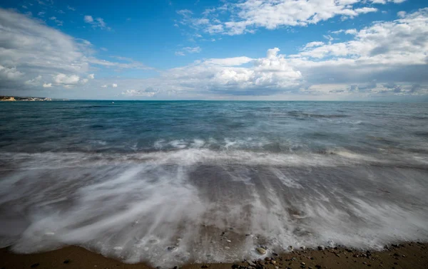 海浪带着卵石和蓝天飞溅在沙滩上 Melanda海岸 Pissouri塞浦路斯 长期曝光摄影 — 图库照片