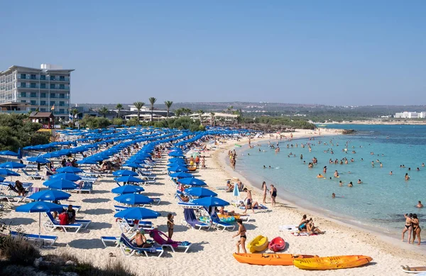 Идиллический пляж с золотым песком и бирюзовой водой с туристами летом — стоковое фото