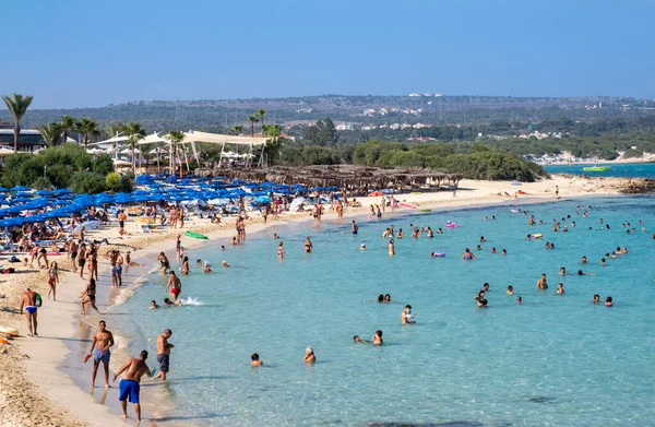 Idyllic beach with golden sand and turquoise water with tourists in summer — Stock Photo, Image