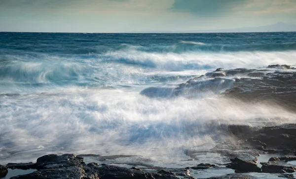 Fırtınalı, rüzgarlı deniz dalgalarını kayalık bir sahile serpmek. — Stok fotoğraf
