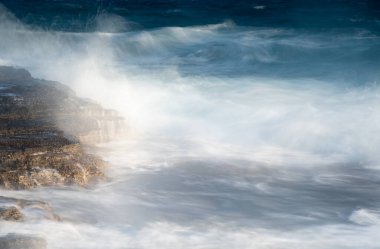 Fırtınalı, rüzgarlı deniz dalgalarını kayalık bir sahile serpmek.