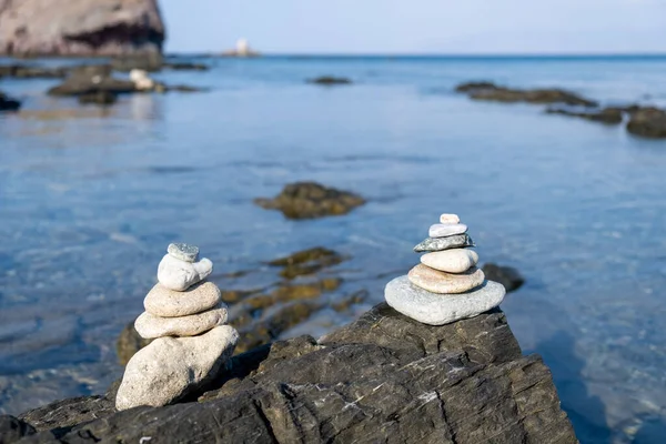 Pirámide de guijarros blancos equilibrados, sobre la roca de una playa rocosa — Foto de Stock