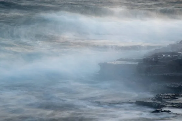 Lungomare roccioso con oceano ondulato e onde che si infrangono sulle rocce. — Foto Stock