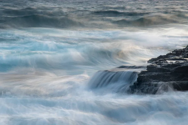 바위에 부딪히는 파도와 파도로 바위로 뒤덮인 바닷가. — 스톡 사진
