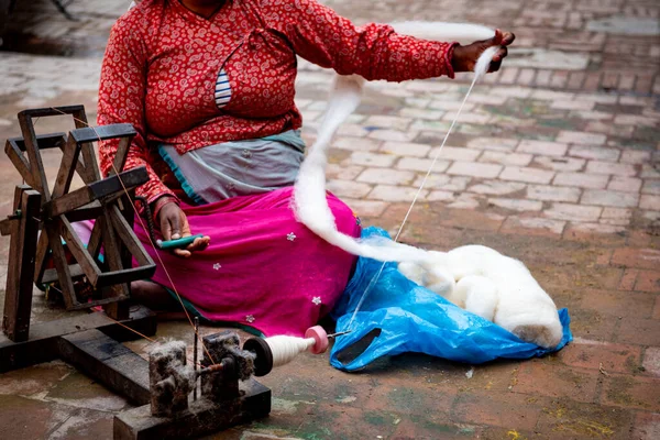 Frau spinnt Baumwollfaden auf einer hölzernen Vintage-Maschine. — Stockfoto