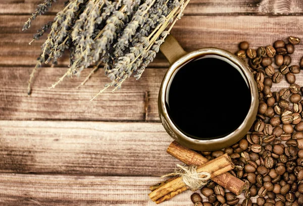 Bir fincan kahve, kahve çekirdekleri, tarçın ve lavanta ahşap arka plan üzerinde. Üstten görünüm.