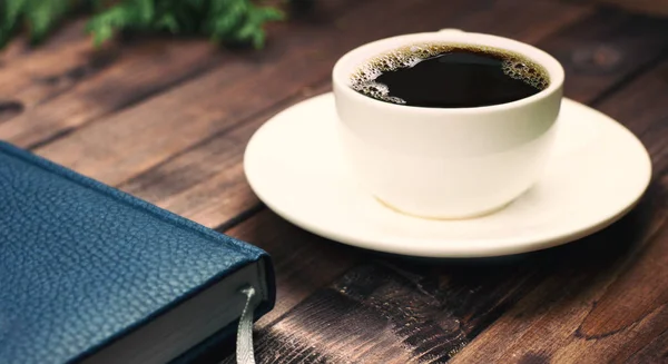 Defter ile ahşap bir masa üzerinde kahve. Yan görünüm.