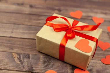 Sevgililer günü hediyesi. Hediye kutusu ahşap arka plan üzerinde kırmızı kurdele ile