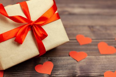 Kırmızı kurdele ve ahşap arka plan üzerinde kalp hediye kutusu