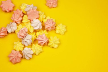 Çok renkli mini meringues sarı bir arka plan, üstten görünüm üzerinde. Metin için yer.