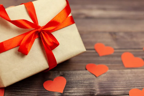 Kırmızı kurdele ve ahşap arka plan üzerinde kalp hediye kutusu