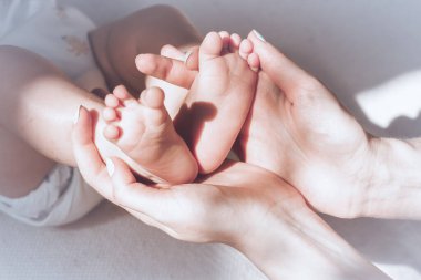 Bebeğin küçük ayakları annesinin kollarındaydı. Anne yeni doğmuş bir bebeğin bacaklarını ya da topuklarını nazikçe okşar, anne sevgisi ve bakımı. Annesi ve çocuğu. Mutlu Aile Konsepti.