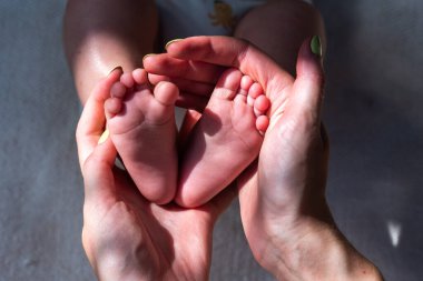 Bebeğin küçük ayakları annesinin kollarındaydı. Anne yeni doğmuş bir bebeğin bacaklarını ya da topuklarını nazikçe okşar, anne sevgisi ve bakımı. Annesi ve çocuğu. Mutlu Aile Konsepti.