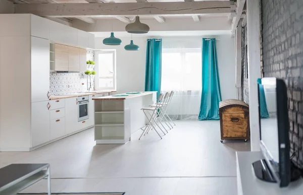 Loft kitchen with white furniture. Island kitchen. Turquoise lamps and curtains. Modern, bright attic apartment.