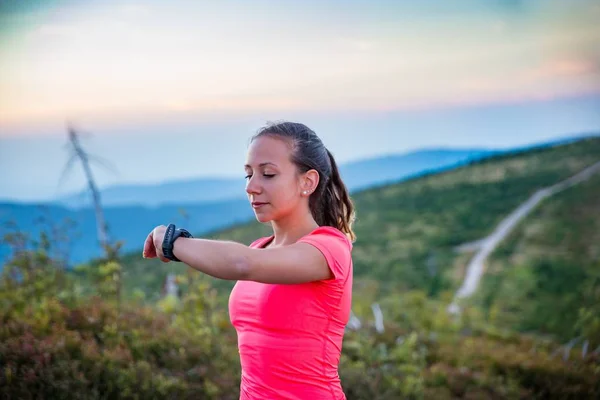 Woman checking time on her sport watch during trail running in mountains. Szczyrk, Beskidy Mountains, Silesian Beskid, Poland