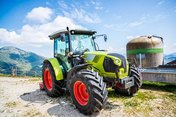Green tractor on farm in Italian Alps mountains