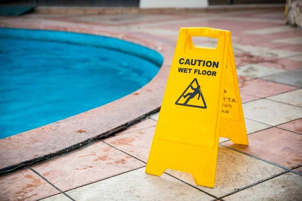 Wet floor yellow precaution information on floor near pool