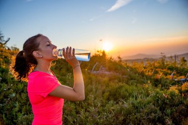 Kadın içme suyu eğitim çalıştırdıktan sonra şişe. Genç kadın çapraz dağlarda çalıştıran.