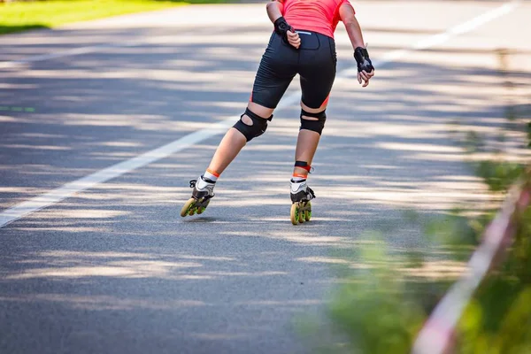Young woman roller skating in the park on asphalt road