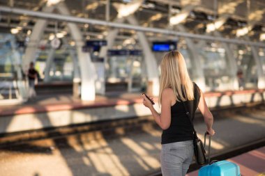 Tren Tren İstasyonu platformu üzerinde bekliyorsun ve online zamanlama kontrol kadın