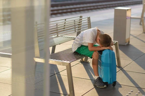 Sad alone boy child waiting alone with his baggage on train station station