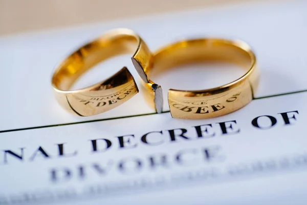 Two broken golden wedding rings divorce decree document. Divorce and separation concept