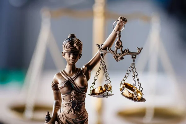 Divorce and family law. Statue of justice and broken wedding rings. Divorce and separation concept