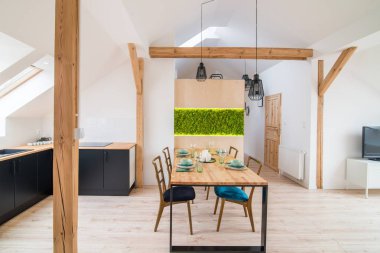 Ahşap masa modern yemek salonunda. Tavan arasındaki modern parlak düz daire. Siyah mutfak dolapları mutfak